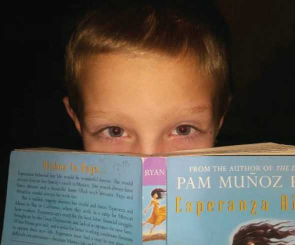 A student reader showing off a book he is reading for the Oregon Battle of the Books, a program supported by McMinnville Education Foundation. 